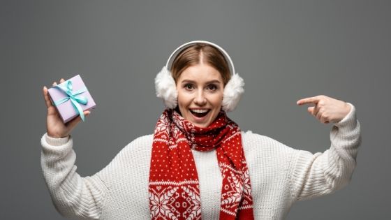 a woman who has a bunch of warm winter higgle clothes and holding a present