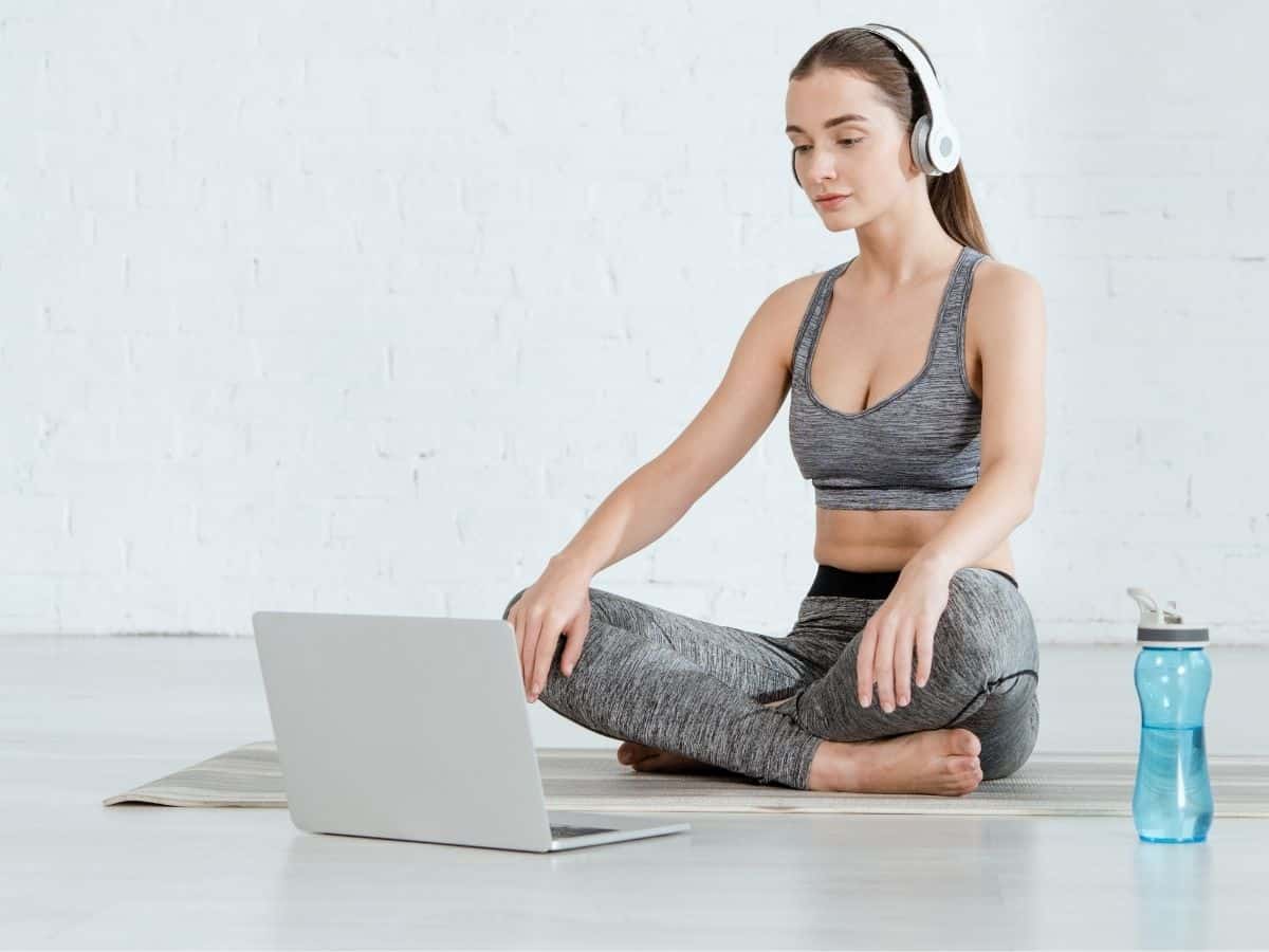 a woman wearing activewear in front of her computer with a water bottle nearby