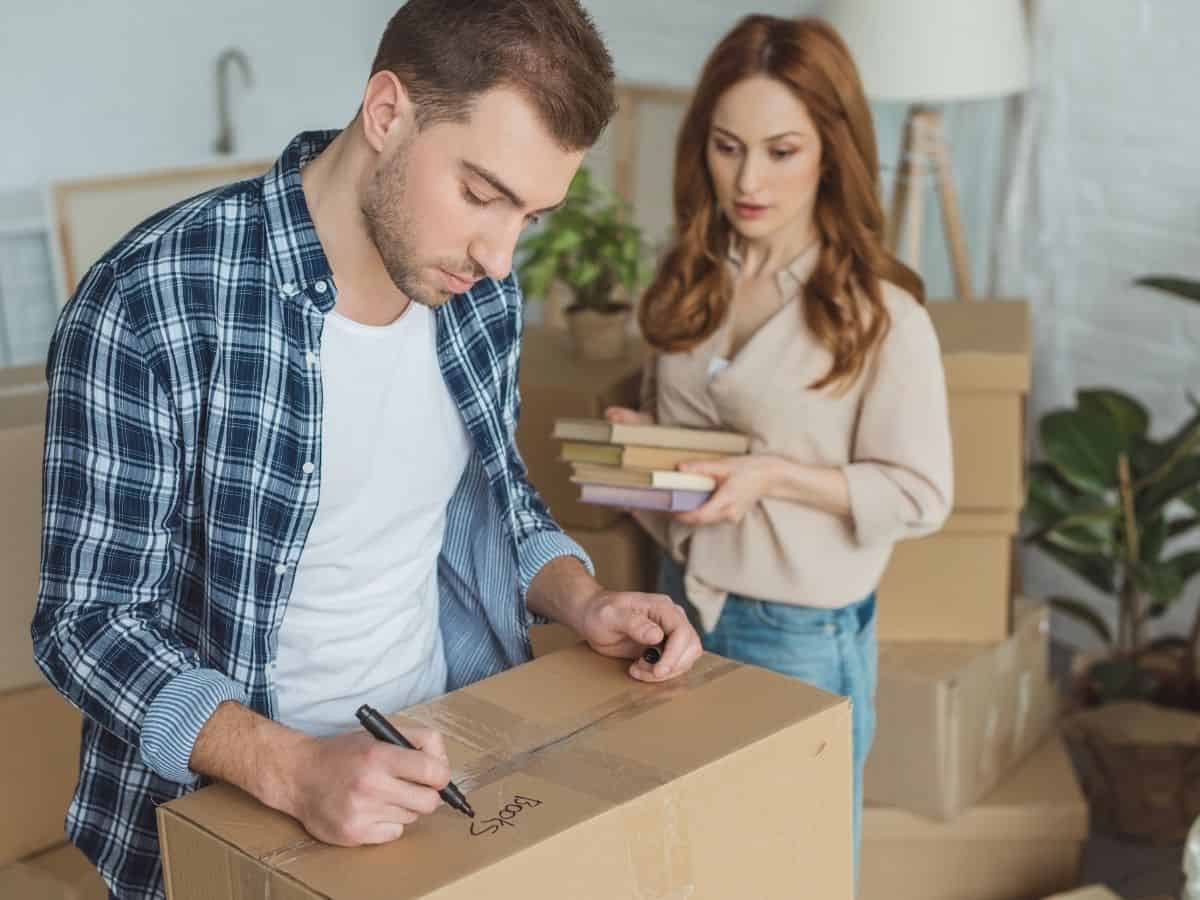 a man and woman packing boxes for their move
