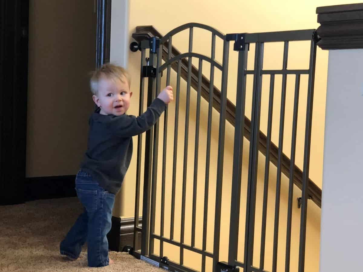 a baby next to a baby gate blocking off a staircase