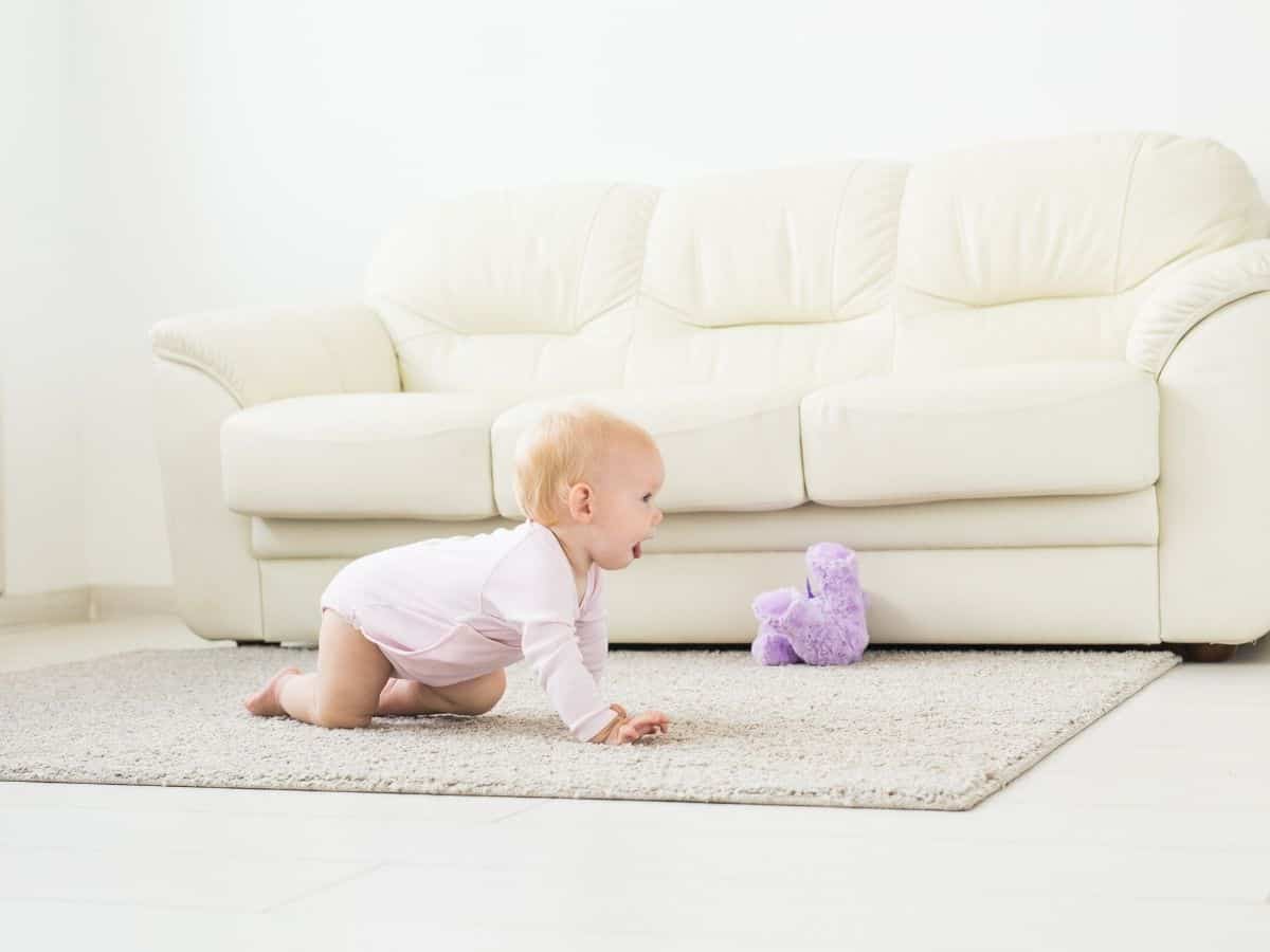 a young baby crawling at home on the floor.