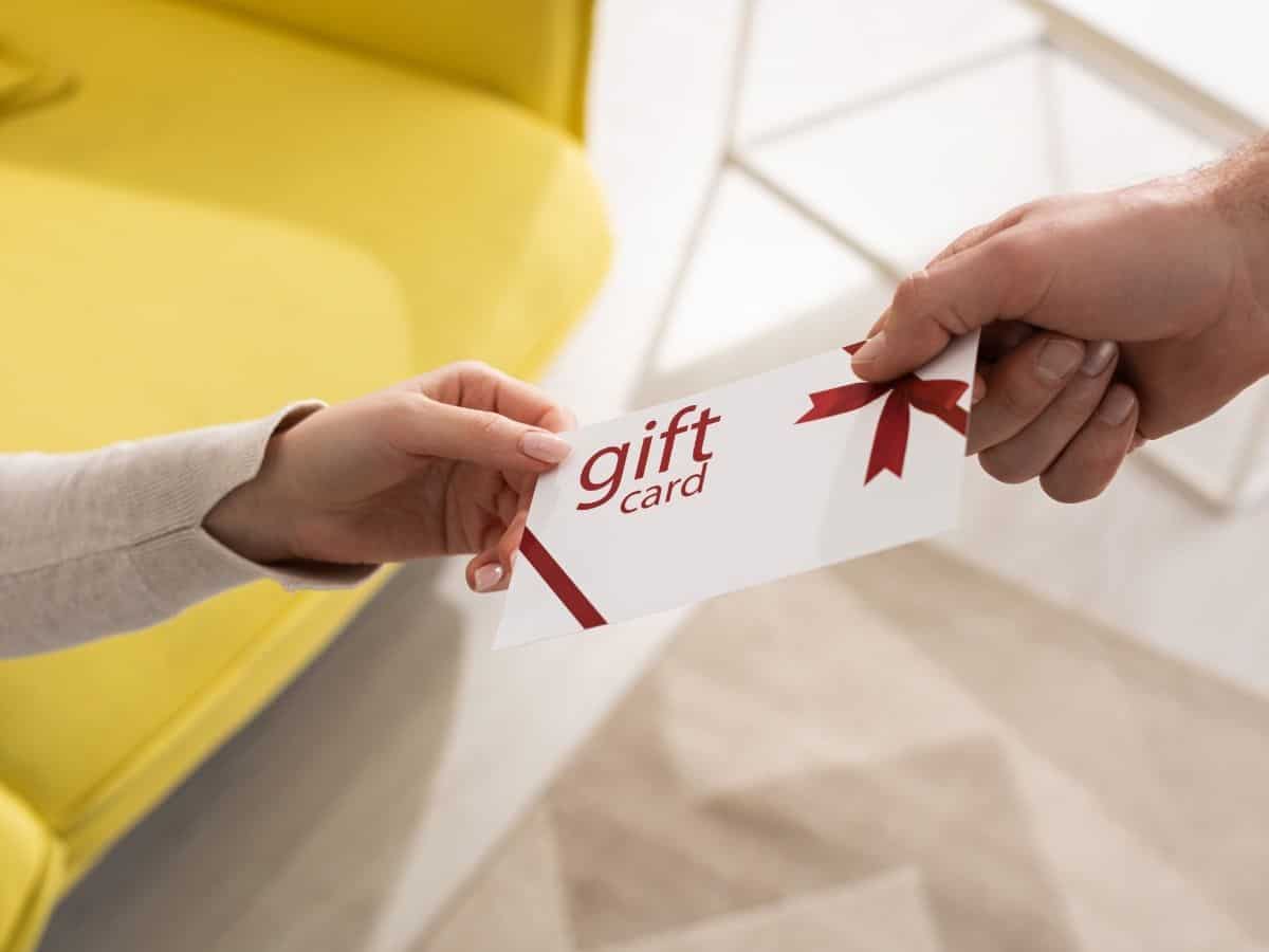 a hand handing a gift card to another hand.