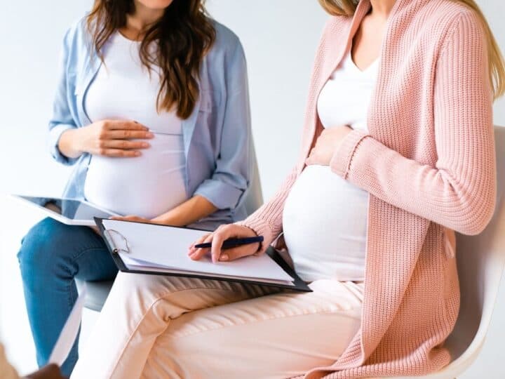 two pregnant women with clipboards sitting beside each other