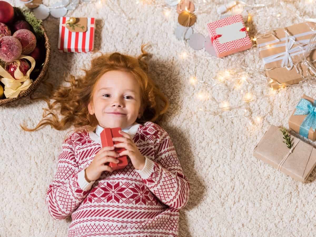 a toddler holding a gift while laying on the floor