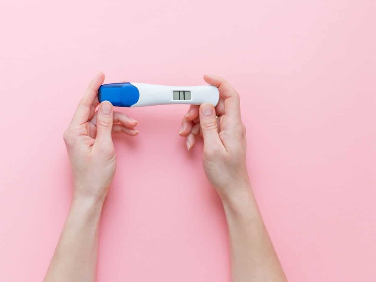 a set of hands holding a positive pregnancy test