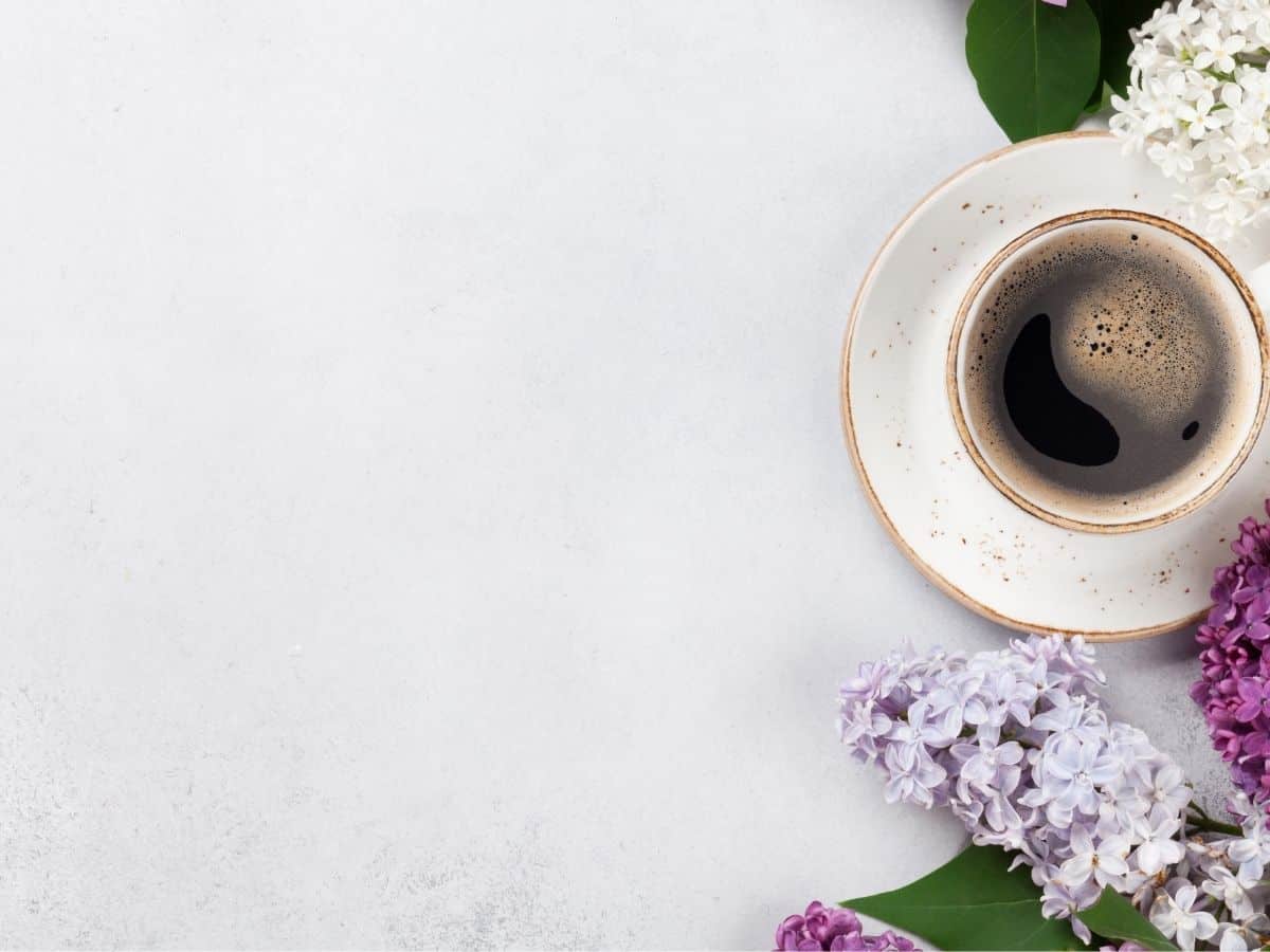 a cup of coffee by some flowers