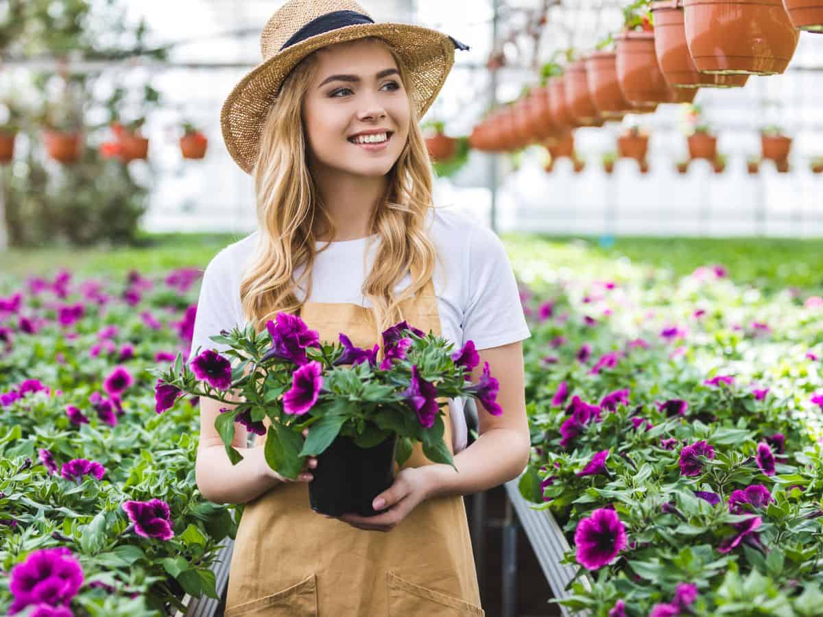 a woman in a greenhouse with lots of flowers