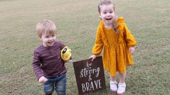 a boy and girl smiling next to a sign that says be strong and brave