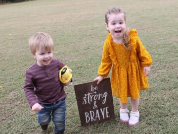 two young kids holding a decorative sign that says be strong and brave