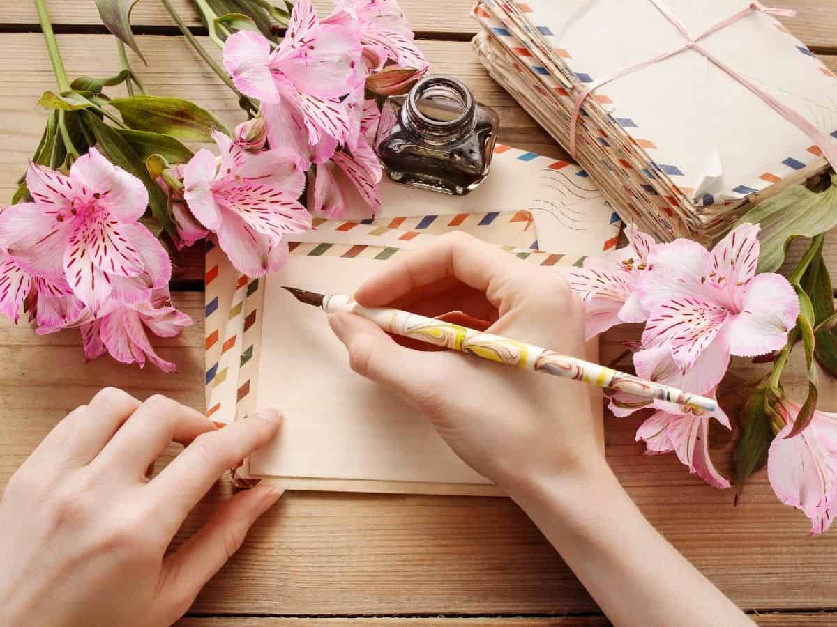 an overhead look at someone writing a letter with flowers by them