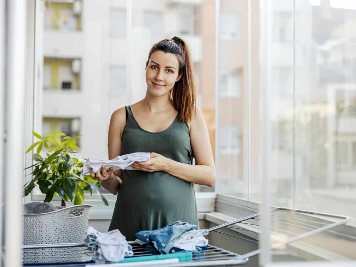 a pregnant woman folding baby clothes