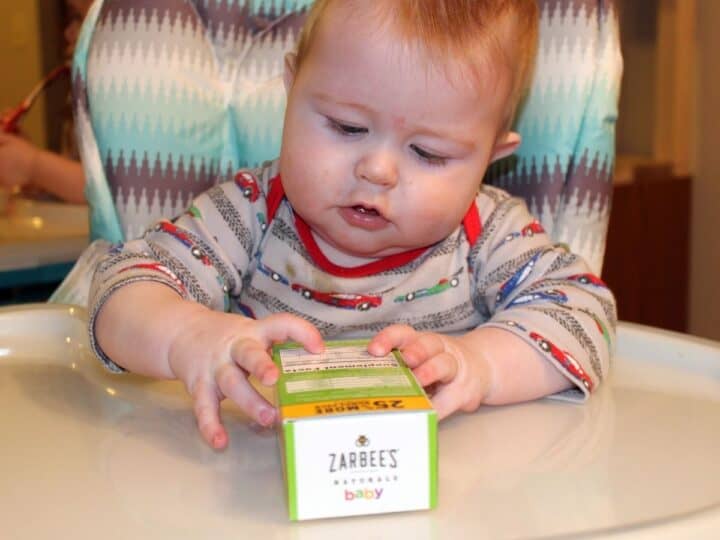 a baby holding a box of zarbees baby cough medicine