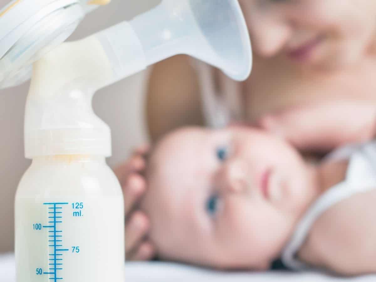 a breast pump filled with breastmilk and a baby with his mom