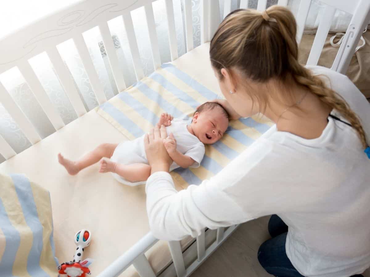 a mom watching her baby sleep in the crib