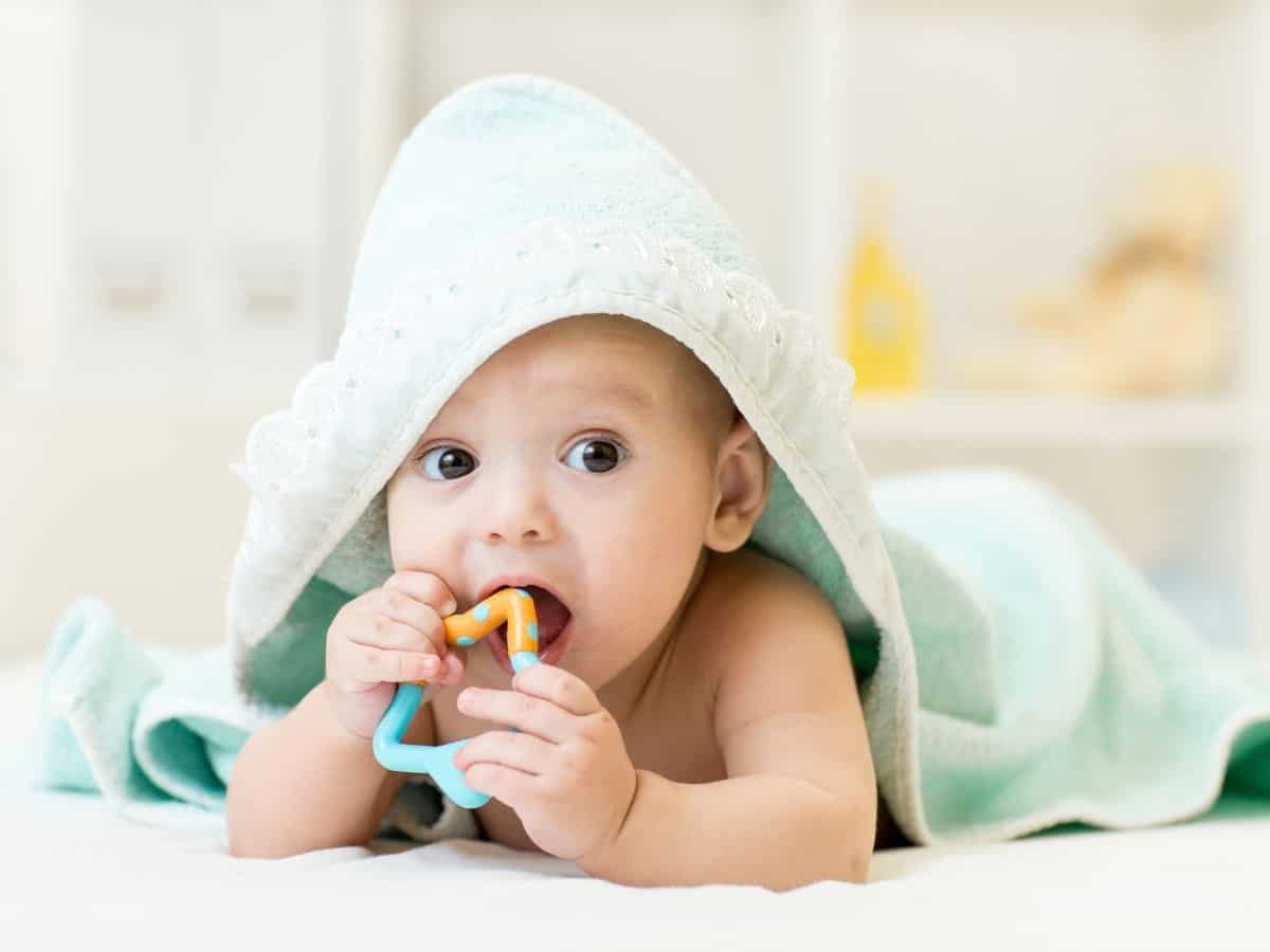 a young baby chewing on a teething toy