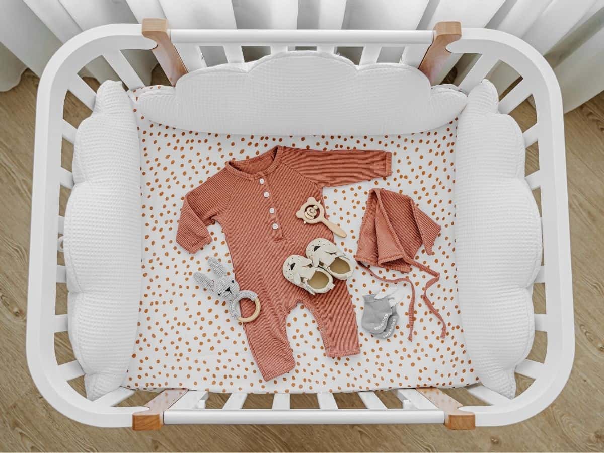 a crib with a set of newborn clothes laid out for baby