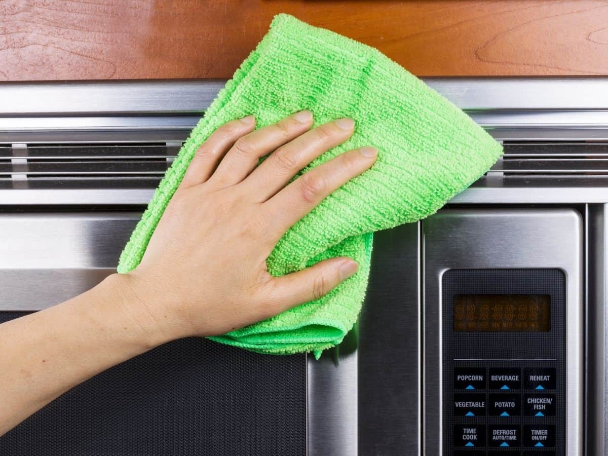 wiping a microwave with a microfiber cloth