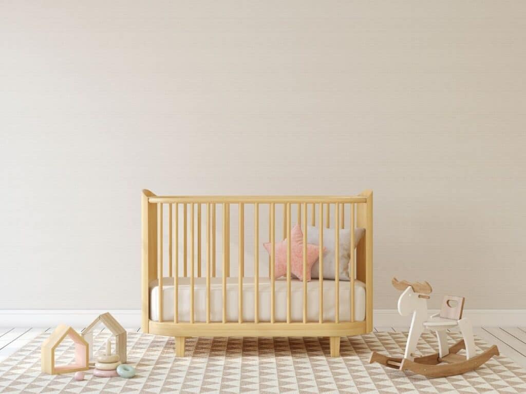 a simple nursery with a crib rocking horse and some decorations