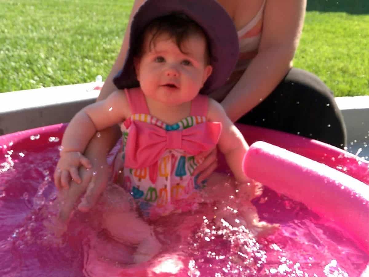 an infant girl in a baby swimming pool with her mom