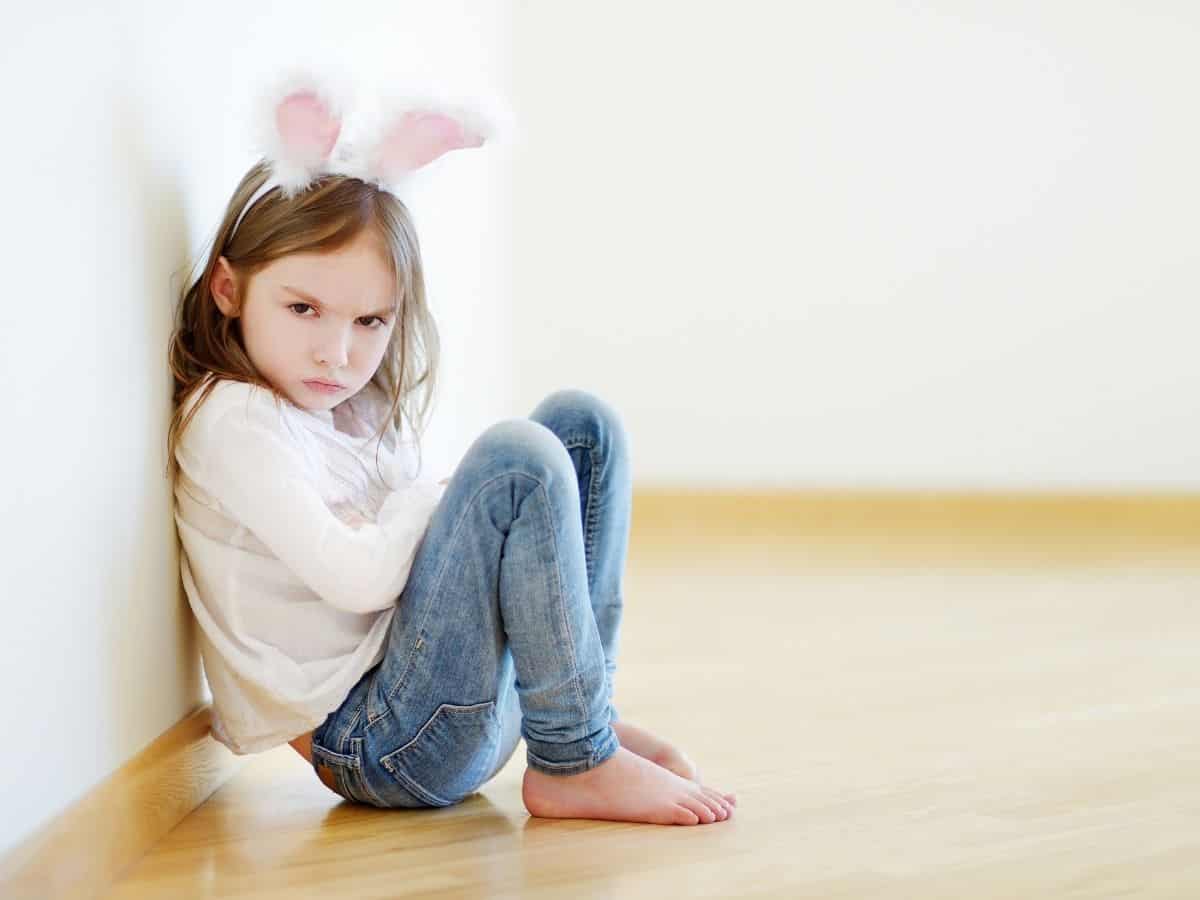 an unhappy toddler girl wearing bunny ears