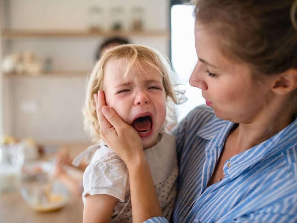 a mom holding her toddler who is throwing a tantrum