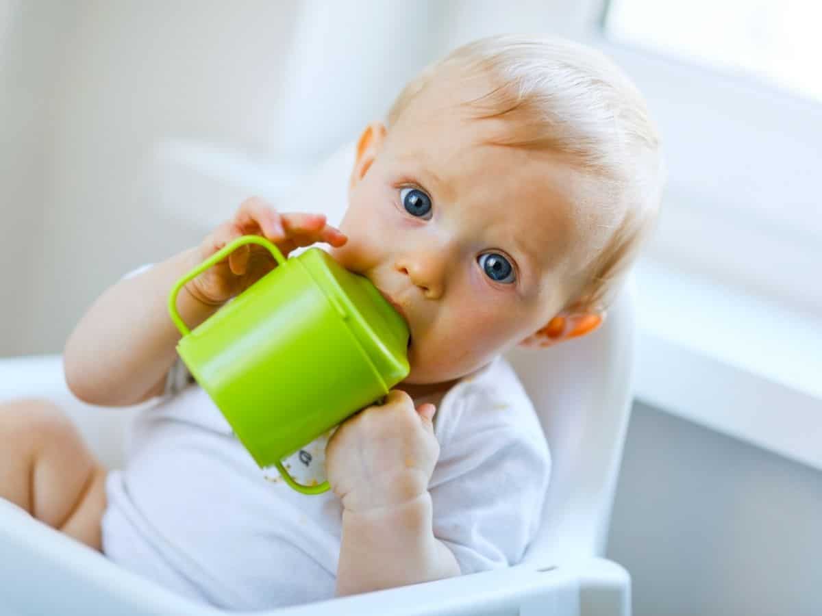 a 1 year old holding a sippy cup