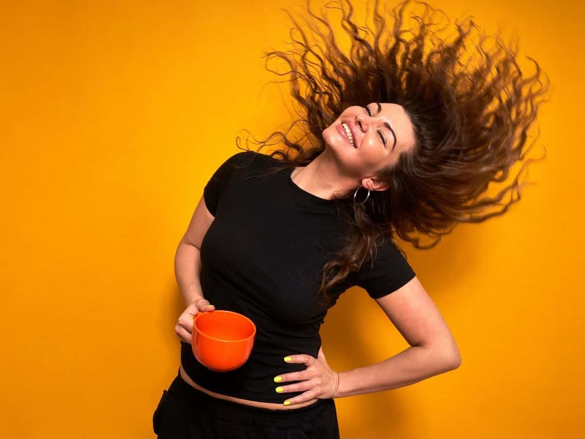 a young woman with lots of energy holding a coffee cup