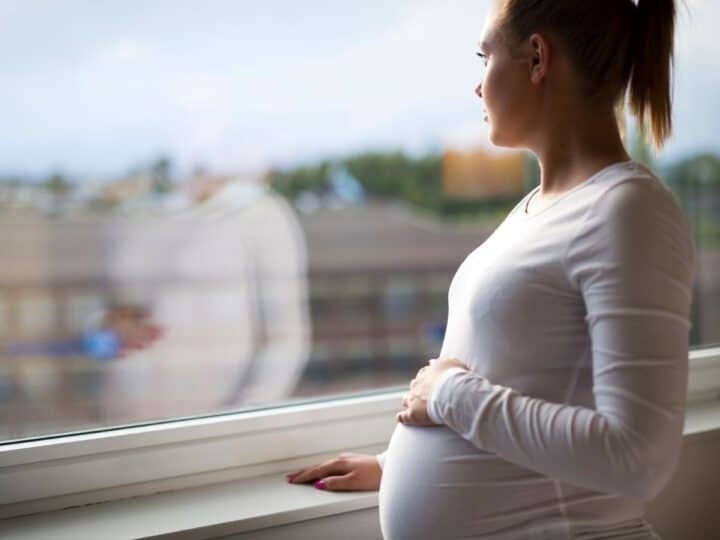 a woman in her third trimester looking out of a hospital window