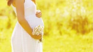 a pregnant woman holding her baby bump during summer