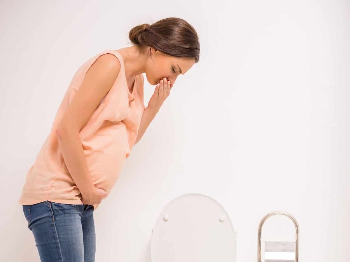 a pregnant woman holding her mouth trying not to throw up