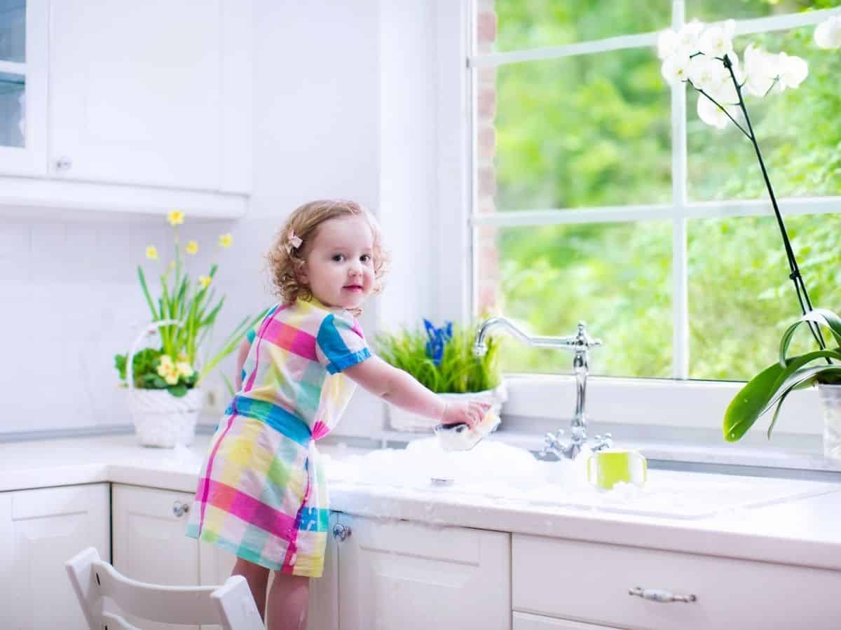a toddler girl helping with the dishes