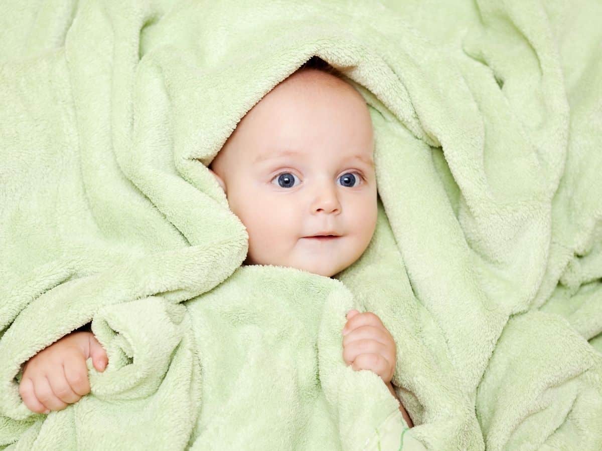 a baby wrapped in a green blanket.