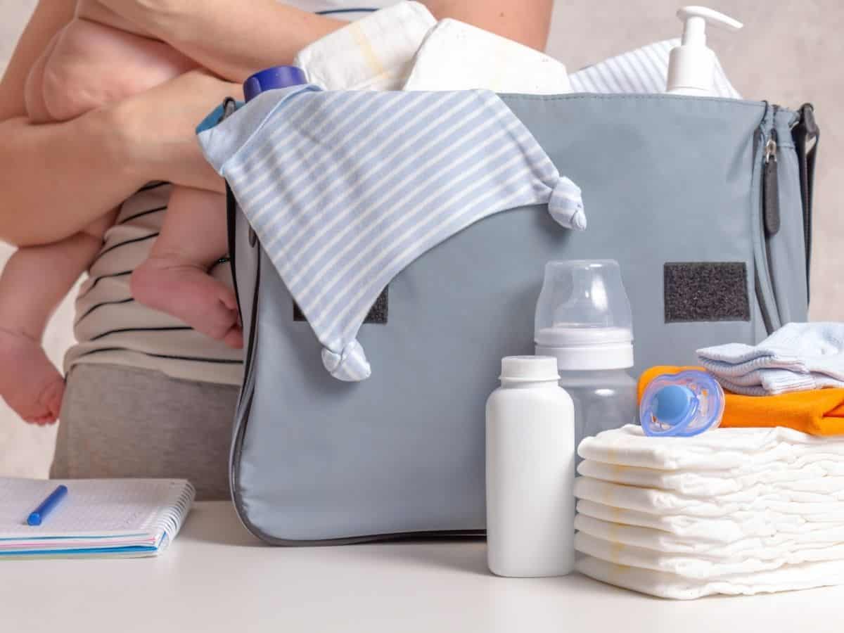 a mom holding her baby while packing her diaper bag