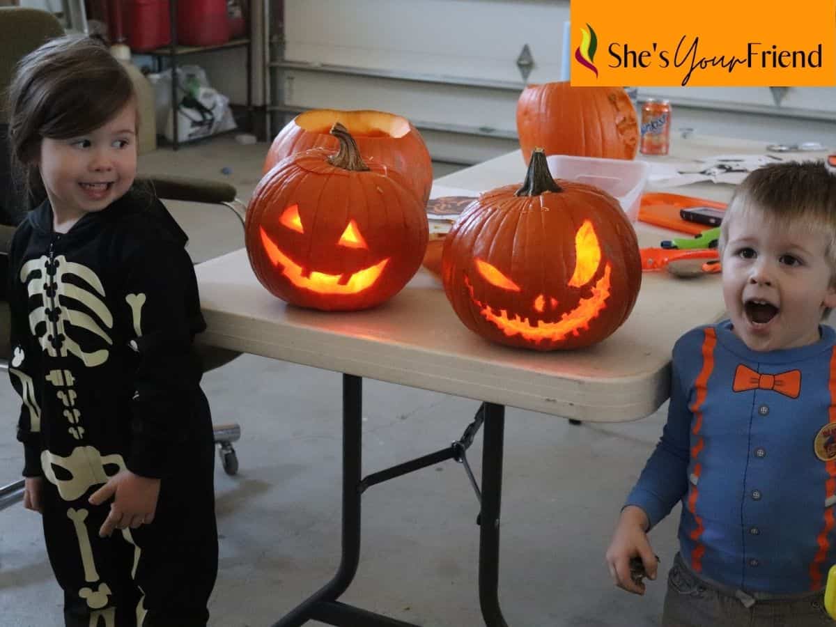 two kids next to their carved pumpkins for halloween