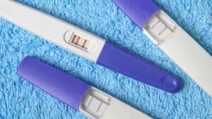three positive pregnancy tests on a blue rug