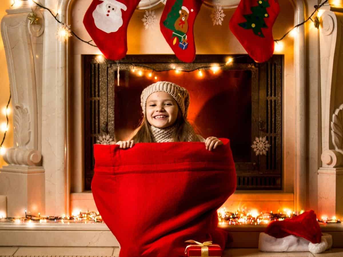 a toddler girl at home by her fireplace with Christmas decorations nearby