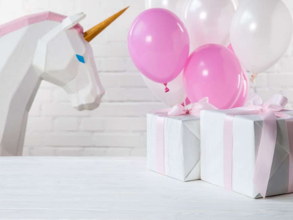 two presents gift wrapped with pink and white balloons and a unicorn