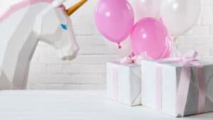 gifts wrapped with pink ribbon at a party with balloons and a unicorn