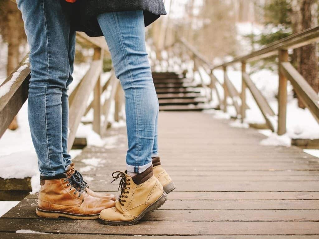 a man and woman close up image of their jeans and boots in the winter