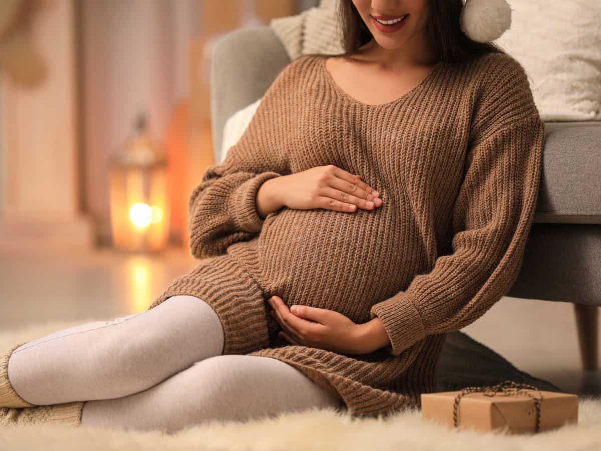 a pregnant woman sitting by a gift box