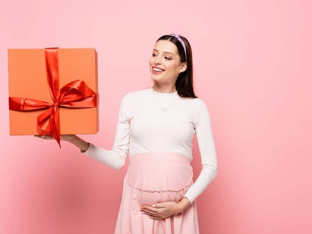 a pregnant mom holding a gift and her growing bump
