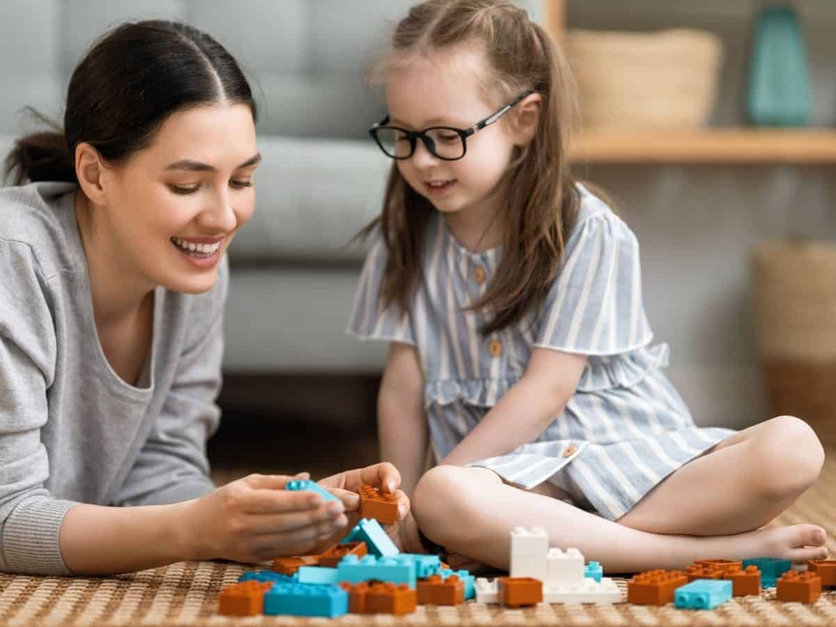 a mom and her daughter building with legos