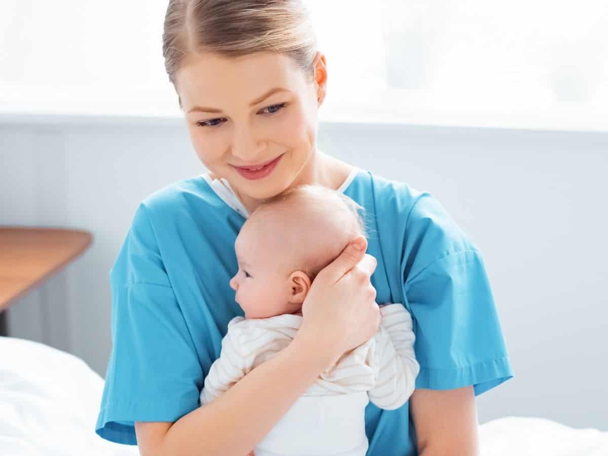 a woman who is holding her new baby while still in a hospital gown