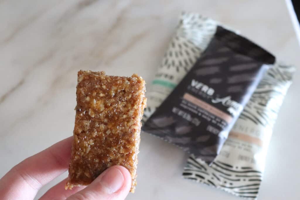 An unwrapped Verb energy bar being held in front of some wrapped energy bars