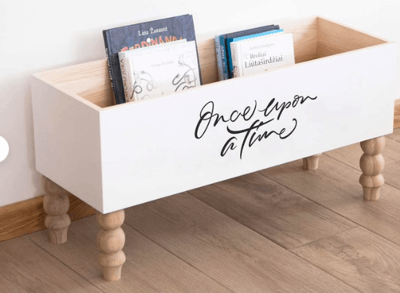 a white painted book shelf with wording that says once upon a time in script font