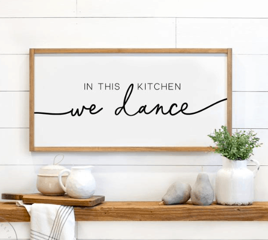 a sign hanging up that says " in this kitchen we dance"