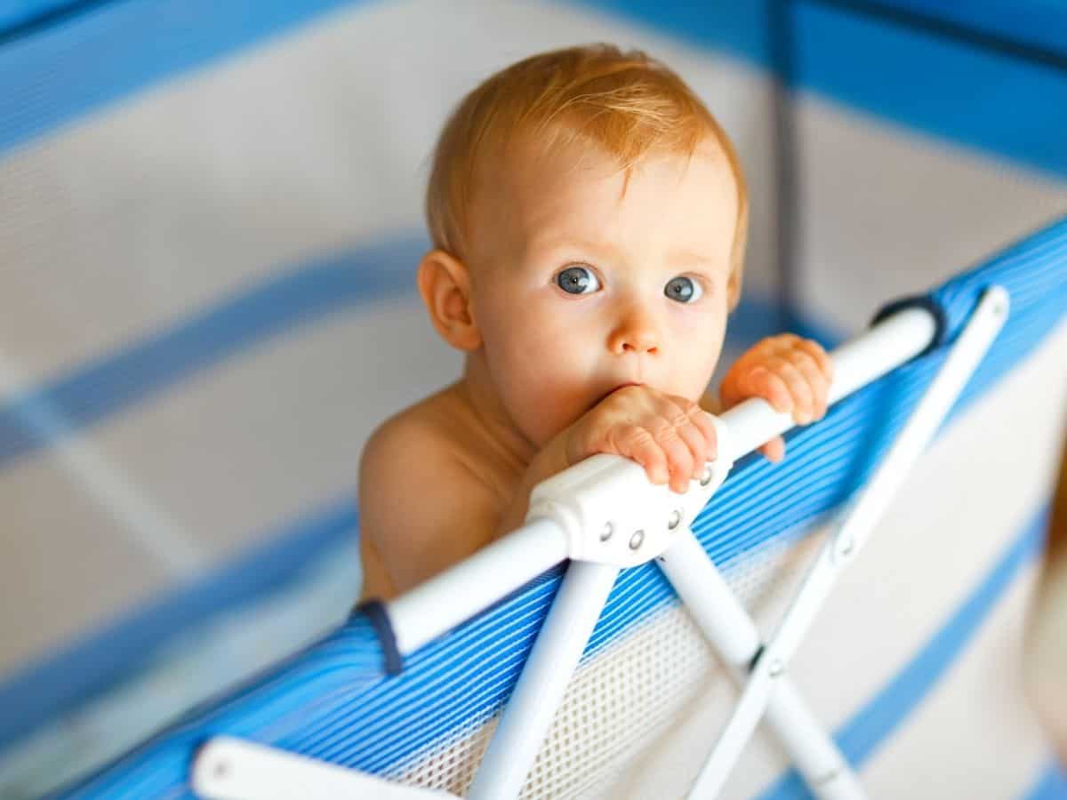 a young child standing up in a pack n play