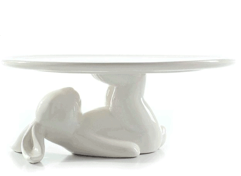 a white cake stand with a bunny holding it up