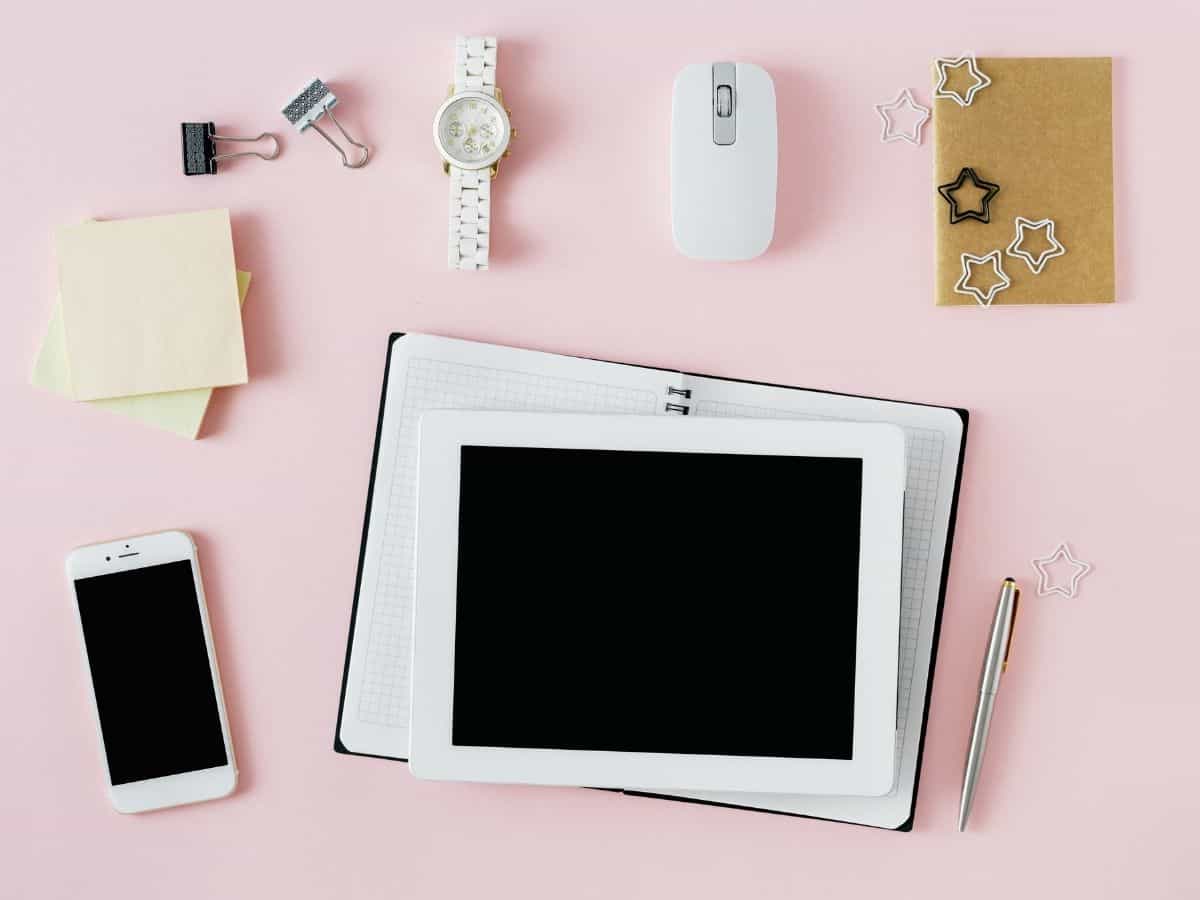 a flatly showing a computer tablet and phone along with a watch a computer mouse and notepads