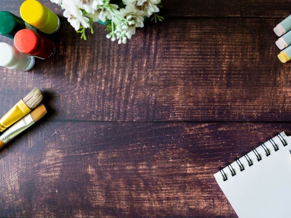 a flatlay image showing a notepad paint brushes and some paint